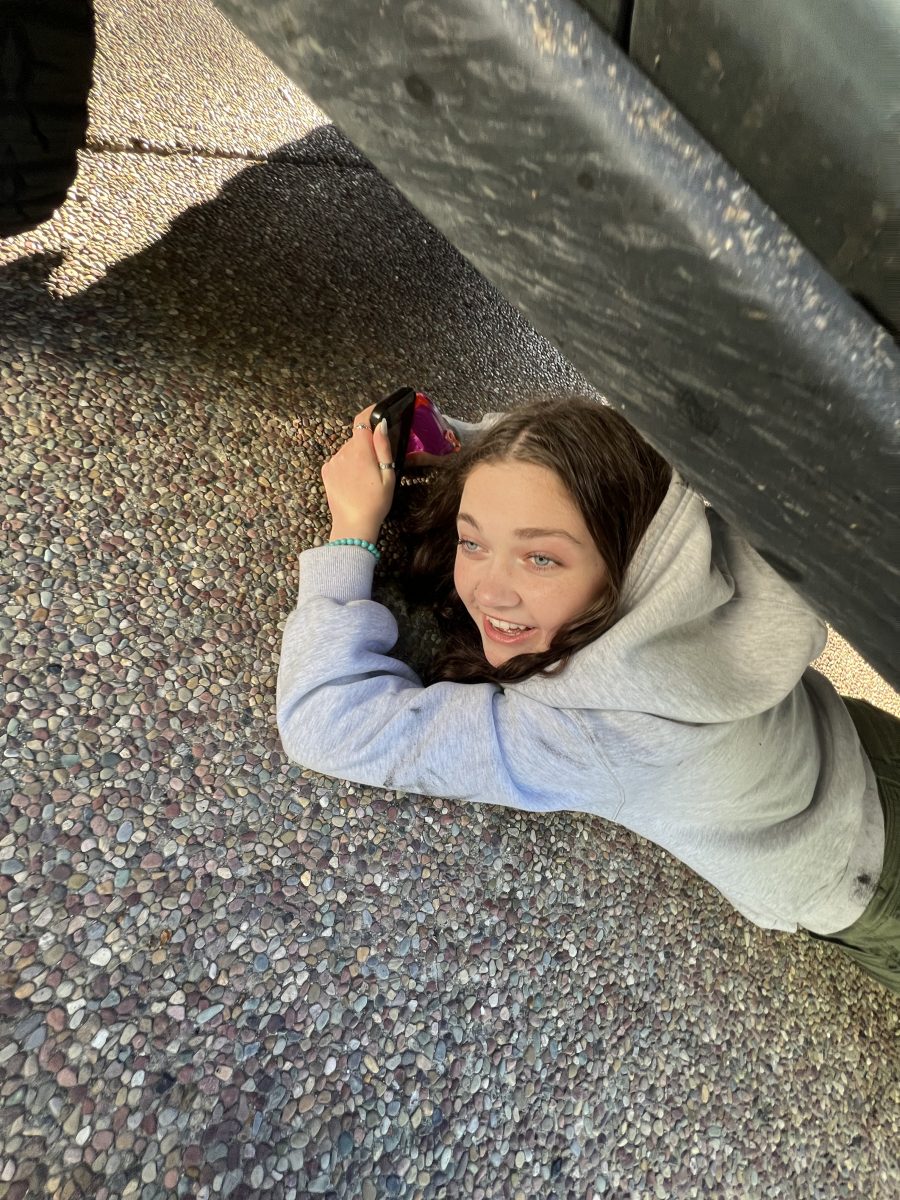 Senior Katie Feldman hides under a car in an attempt to squirt her targets early in the morning. 